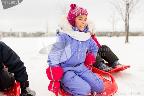 Image of little girl on snow saucer sled in winter