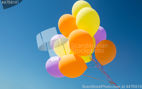 Image of close up of colorful helium balloons in blue sky