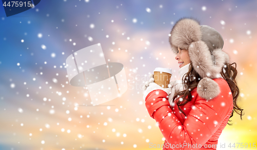 Image of woman in winter fur hat with coffee over snow