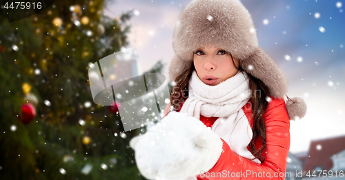 Image of woman blowing to snow over christmas tree