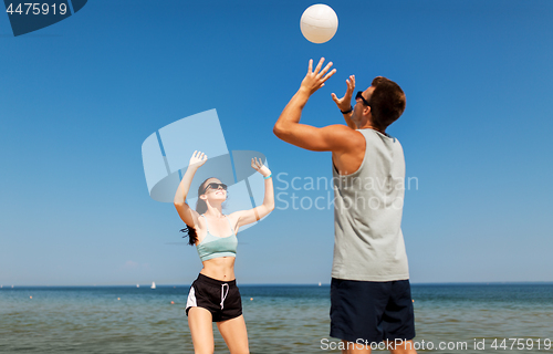 Image of happy couple playing volleyball on summer beach