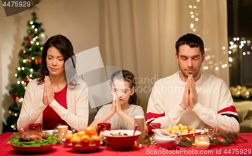 Image of family praying before meal at christmas dinner