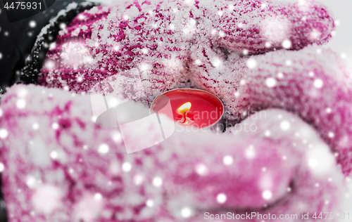 Image of close up of hands in winter mittens holding candle