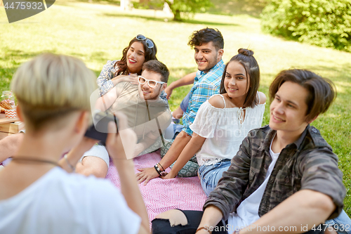 Image of friends photographing at picnic in summer park