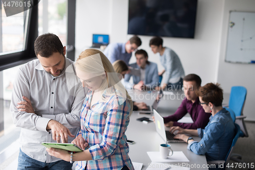 Image of Two Business People Working With Tablet in office