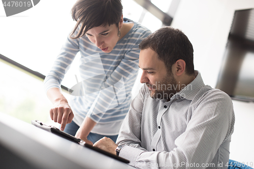 Image of Two Business People Working With Tablet in startup office