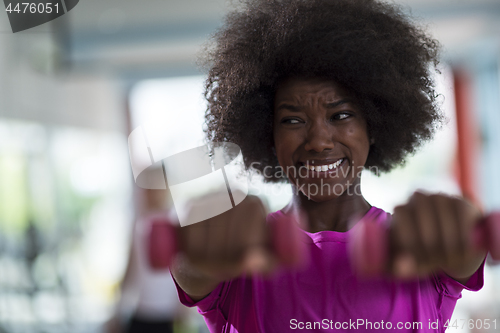 Image of woman working out in a crossfit gym with dumbbells