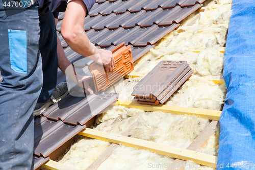 Image of a roofer laying tile on the roof