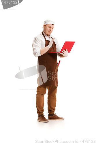 Image of Serious butcher posing with a laptop isolated on white background