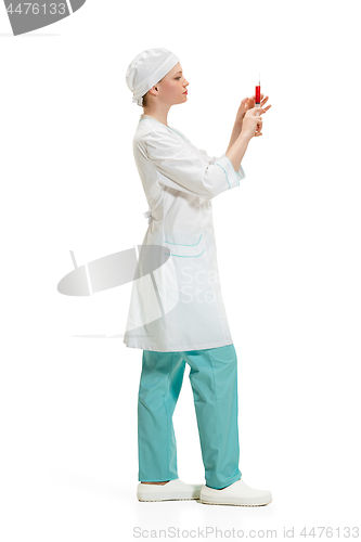 Image of beautiful young woman doctor in medical robe holding syringe in hand.