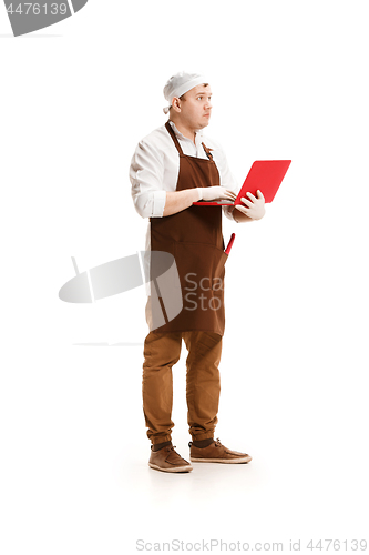 Image of Serious butcher posing with a laptop isolated on white background