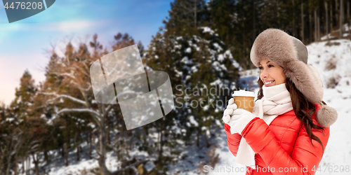 Image of woman in fur hat with coffee over winter forest