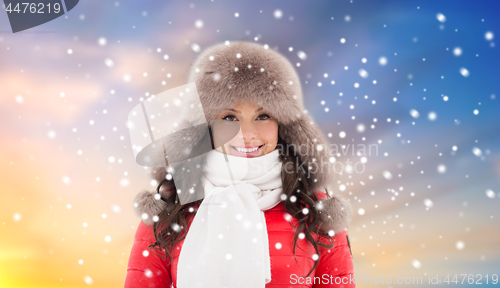 Image of happy woman in winter fur hat over sky and snow