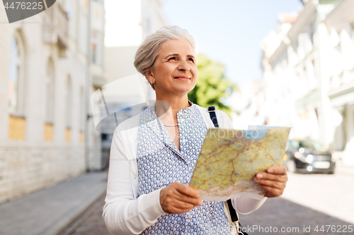Image of senior woman or tourist with map on city street