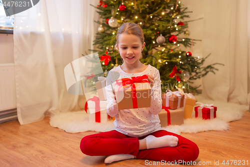 Image of smiling girl with christmas gift at home
