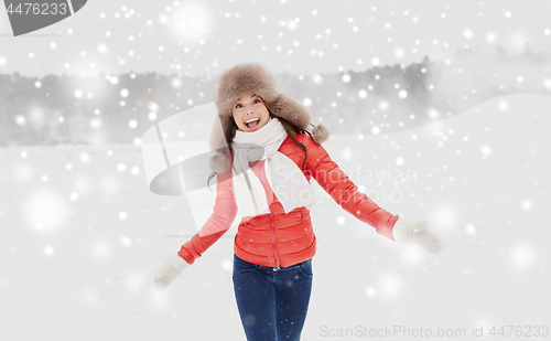 Image of happy woman in winter fur hat having fun outdoors