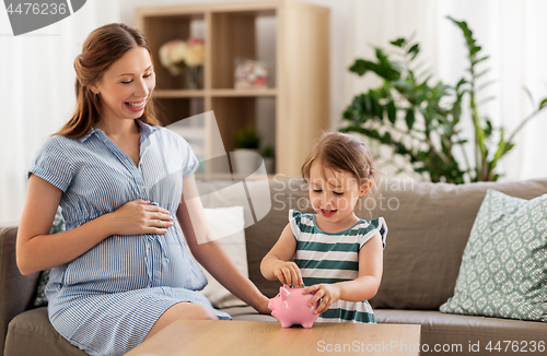 Image of pregnant mother and daughter with piggy bank