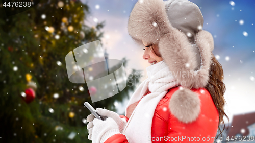Image of woman with smartphone over christmas tree