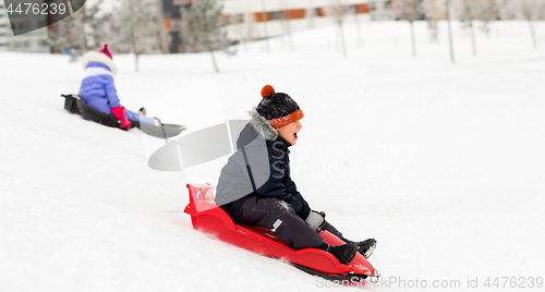 Image of happy kids sliding on sleds down hill in winter