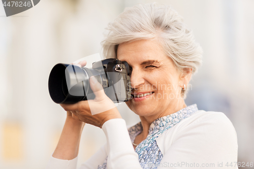 Image of senior woman photographing by digital camera