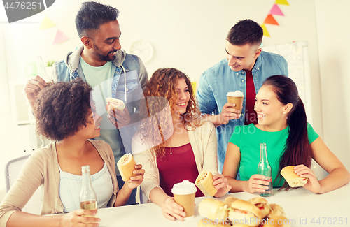 Image of happy friends or team eating at office party