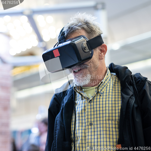 Image of Senior man wearing virtual reality goggles watching virtual reality presentation.