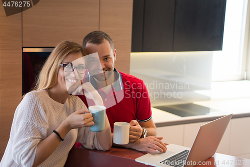 Image of couple drinking coffee and using laptop at home