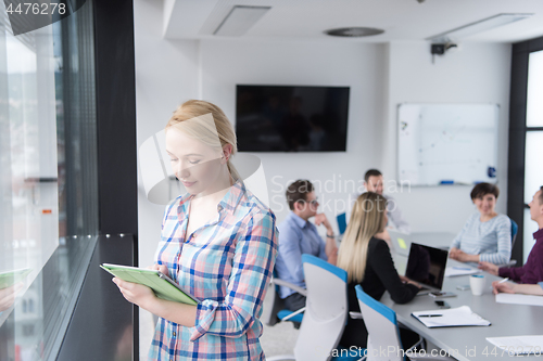 Image of Pretty Businesswoman Using Tablet In Office Building by window