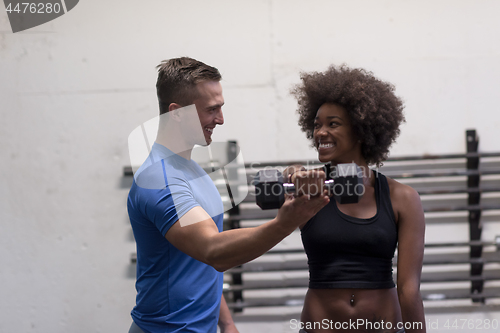 Image of black woman doing bicep curls with fitness trainer