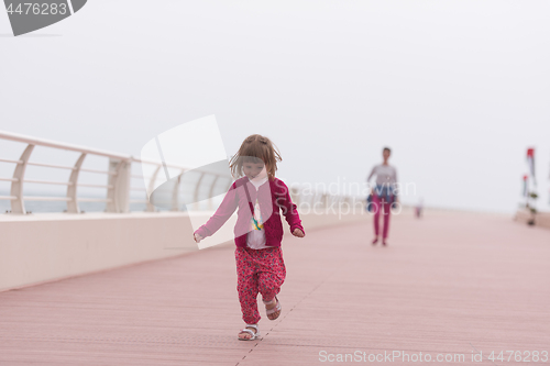 Image of mother and cute little girl on the promenade by the sea