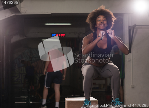 Image of black female athlete is performing box jumps at gym