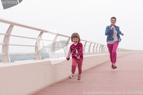 Image of mother and cute little girl on the promenade by the sea