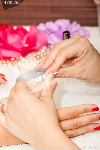 Image of The esthetician removes the old nail polish with a cotton and remover