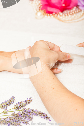 Image of The beautician polish the client\'s nails before putting nail polish