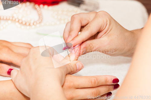 Image of The esthetician removes the old nail polish with a cotton and remover