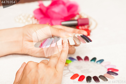 Image of Hands of a woman who chooses the color of her nail polish