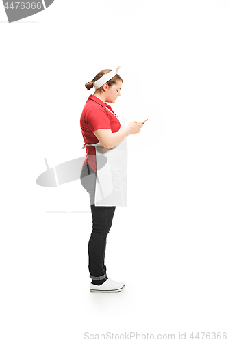 Image of Portrait of cute smiling woman with mobile phone in her hands in the studio, isolated on white background
