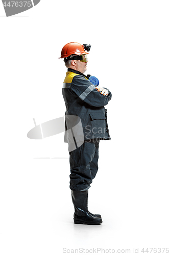 Image of The studio shot of senior bearded male miner standing at the camera on a white background.