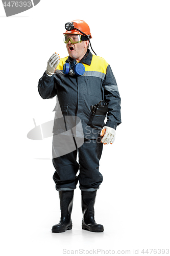 Image of The studio shot of senior bearded male miner standing at the camera on a white background.