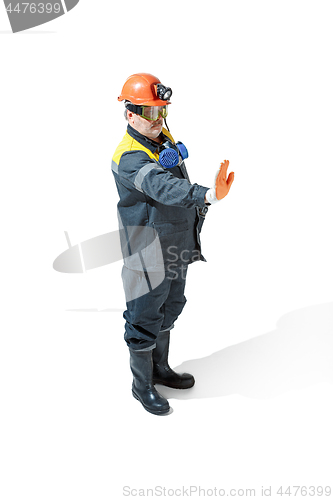 Image of The studio shot of senior bearded male miner standing at the camera on a white background.