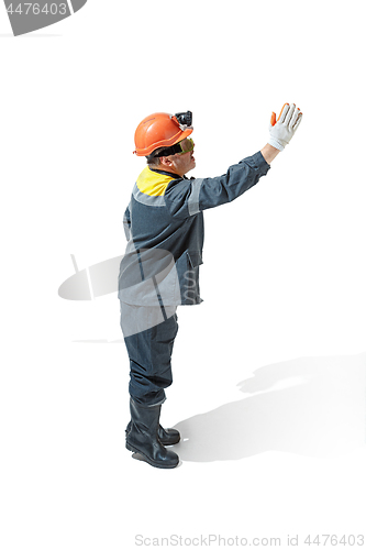 Image of The studio shot of senior bearded male miner standing at the camera on a white background.