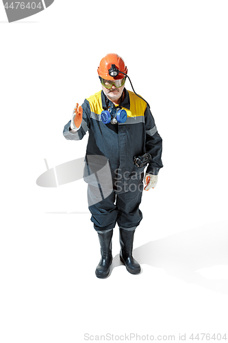 Image of The studio shot of senior bearded male miner standing at the camera on a white background.