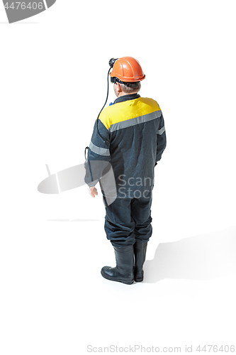 Image of The studio shot of senior bearded male miner standing at the camera on a white background.