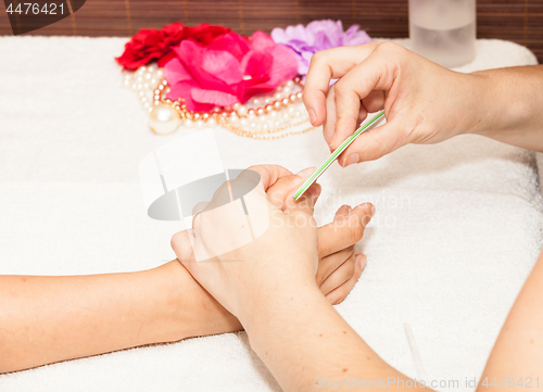 Image of The beautician polish the client\'s nails before putting nail polish