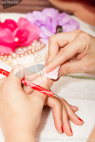 Image of The esthetician removes the old nail polish with a cotton and remover