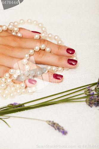 Image of Hands of a woman with red nail polish posed by an esthetician