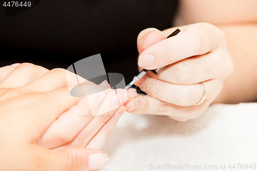 Image of Laying nail polish on a woman\'s hands