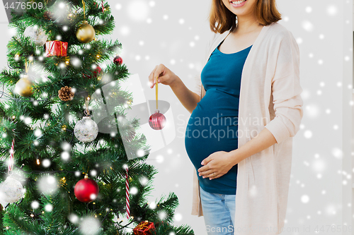 Image of pregnant woman decorating christmas tree