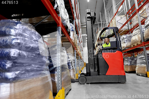 Image of male loader operating forklift at warehouse