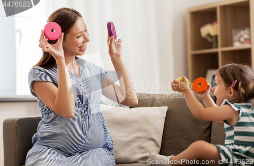 Image of pregnant mother and daughter with toy blocks